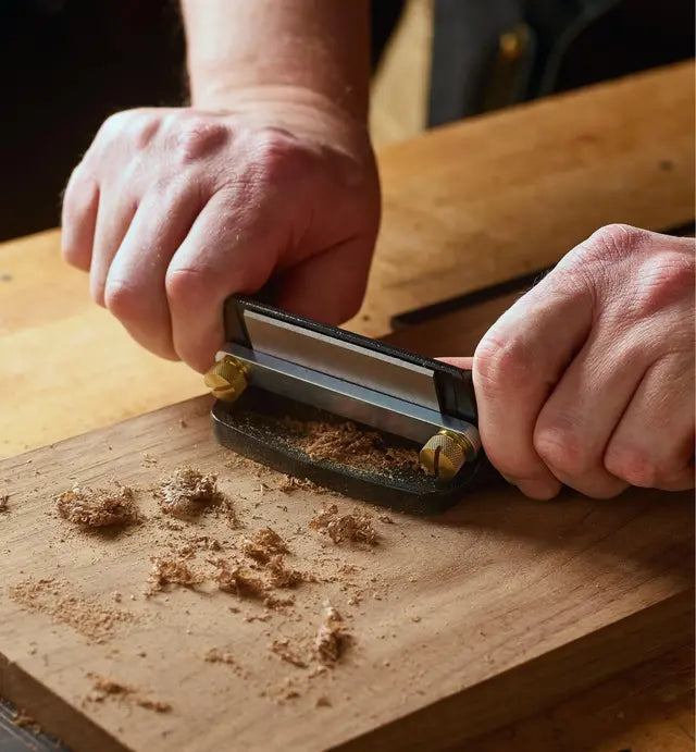 Woodworking using the Veritas Cabinet Scraper to finish a piece of timber.