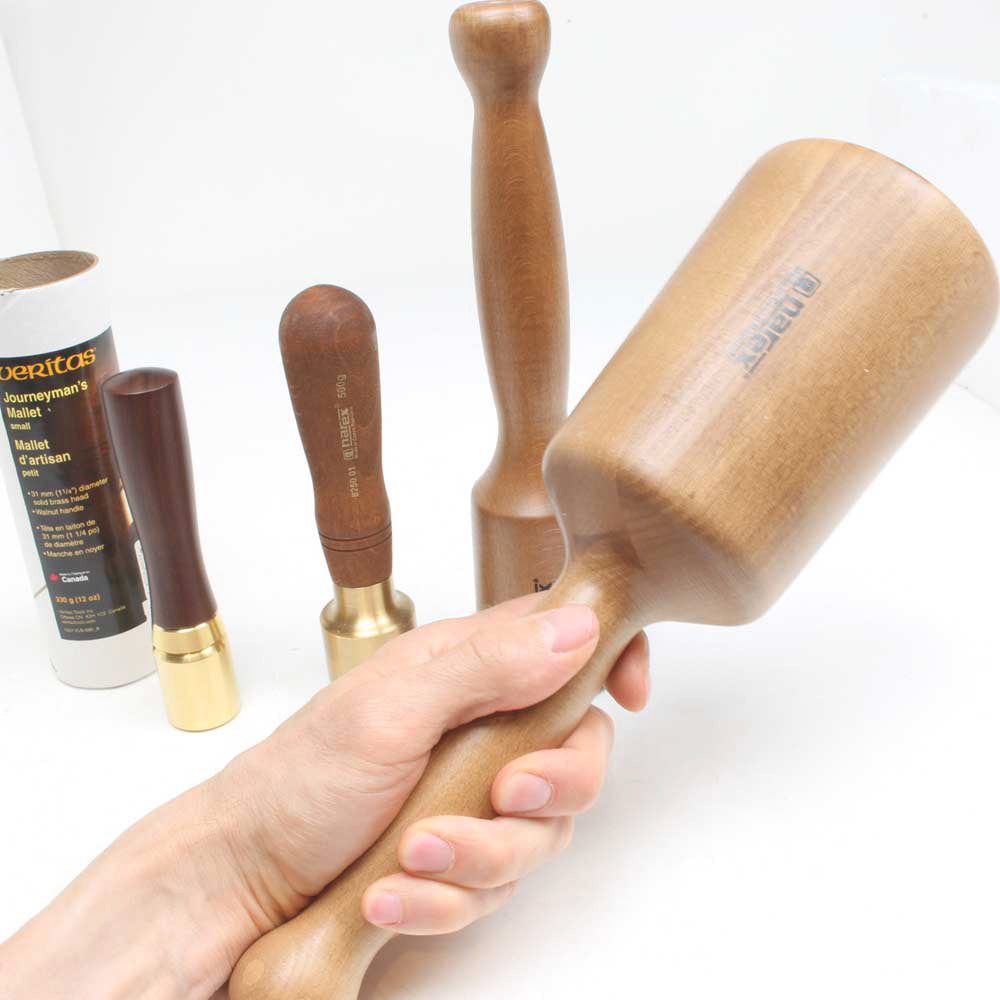 Carving mallet held in hand with three other sizes shown for comparison