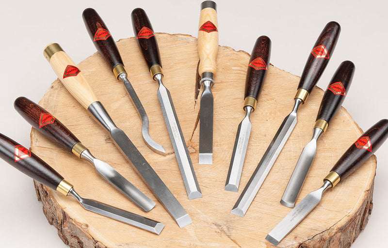 Henry Taylor Woodworking Chisels displayed on top of a slab of a tree.
